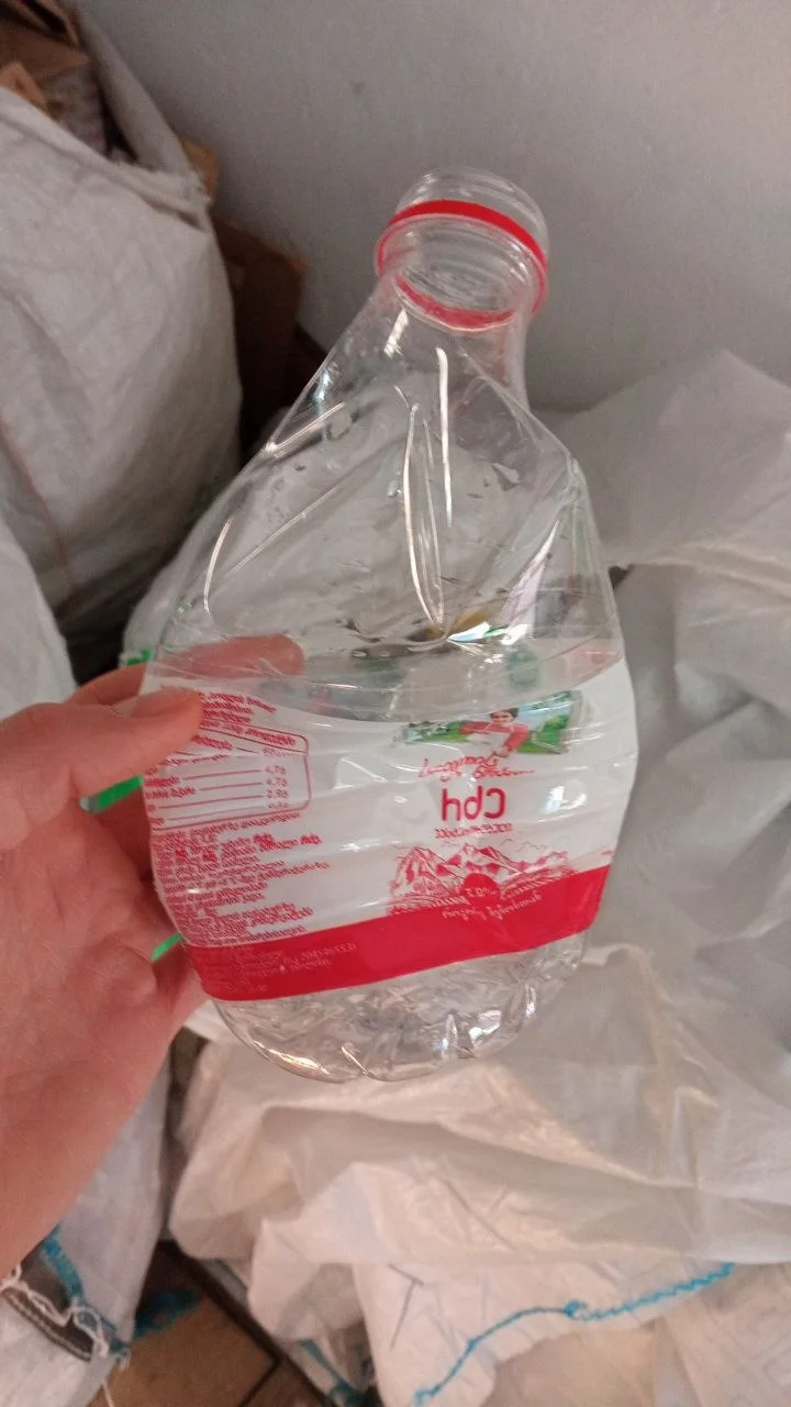 Crushed plastic water bottle held in hand ready for recycling